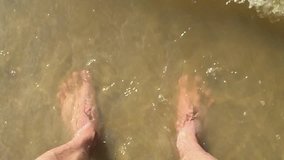 feet waves of sea slow motion video. male tourist is man standing with his feet in the ocean of water splashing on his feet