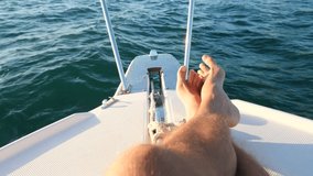 A view from above of a person's feet and wet inside waves of blue sea water, while the boat is moving fast. Slow motion video, 4k
