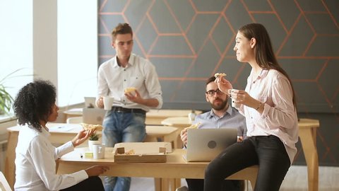 Business team of young people enjoying eating pizza together, millennials group talking having fun sharing lunch in cozy office, good relationships at work, food delivery service and catering