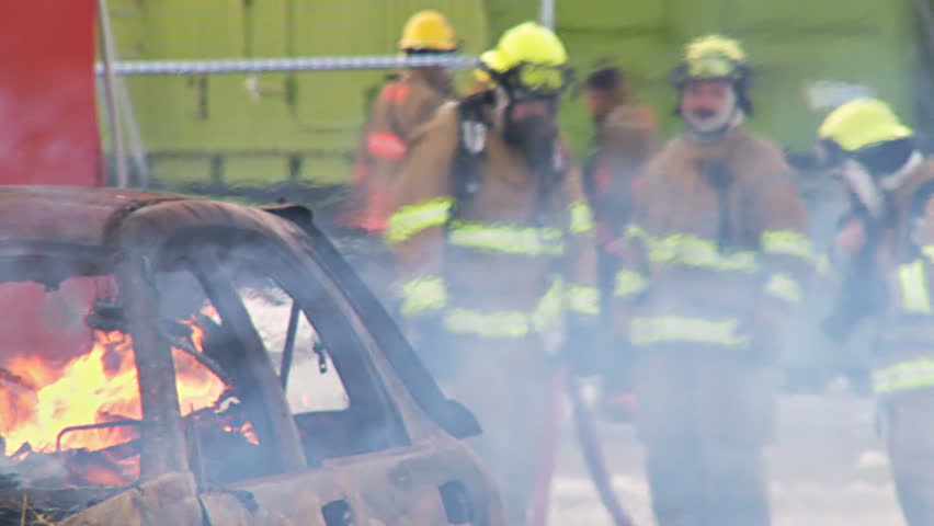 HOMER, AK CIRCA 2012: Volunteer firefighters approach a burning car 