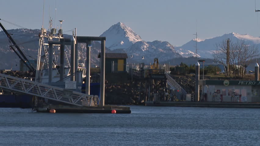 HOMER, AK - CIRCA 2012: Classic fishing boat moves through harbor with scenic