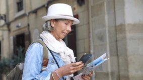 Senior woman visiting Spanish city, using smartphone and map