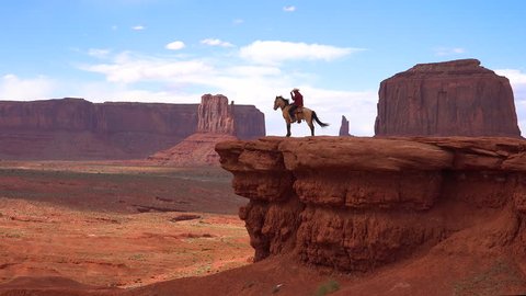 CIRCA 2010s - Monument Valley Navajo Tribal Park, Utah - A cowboy sits on a horse on a cliff in Monument Valley, Utah.