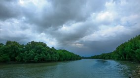 Time lapse: The dark sky and cloudy is moving over the river and forest and the rain is coming.