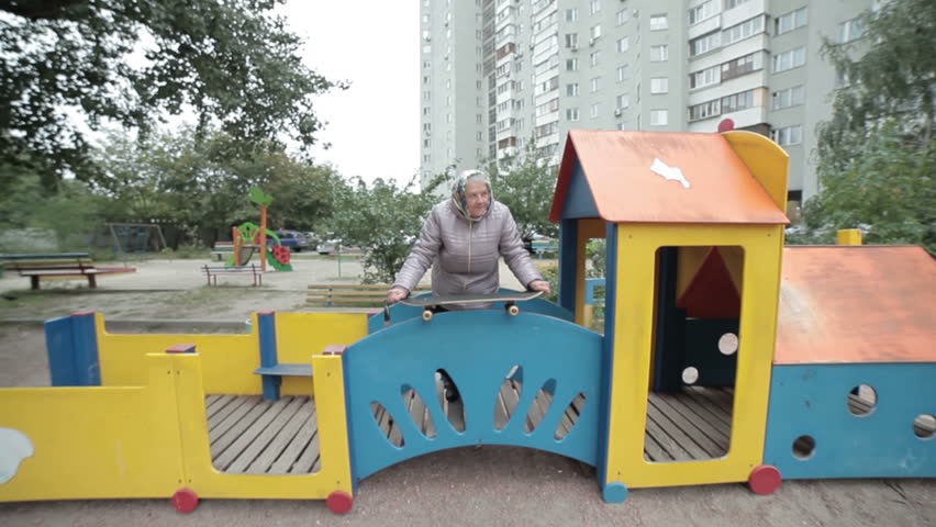 Grandmother on the playground, in her hands a skateboard.