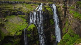 Picturesque landscape of a mountain waterfall and traditional nature of Iceland. 4K Time Lapse Footage.