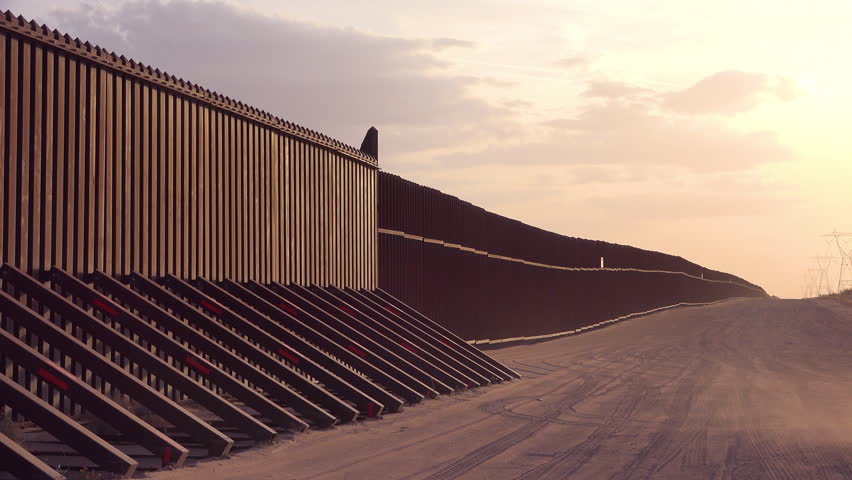 CIRCA 2010s - U.S.-Mexico border - Dust blows at sunset at the border wall at the US Mexico border near Imperial sand dunes, California.