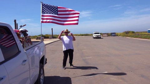 CIRCA 2010s - U.S.-Mexico border - An American minuteman salutes the Border Patrol at the U.S. Mexico border with his flag and pickup truck.