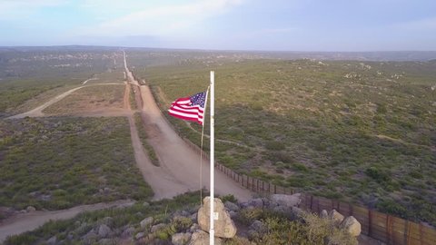 CIRCA 2010s - U.S.-Mexico border - The American flag flies over the U.S. Mexico border wall in the California desert.