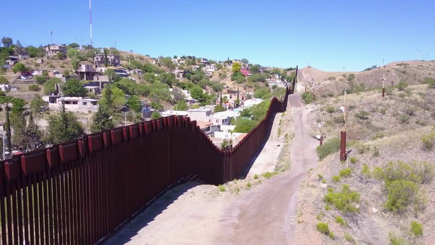 CIRCA 2010s - U.S.-Mexico border - Forward aerial along the U.S Mexican border wall fence reveals the town of Nogales.