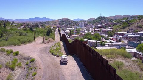 CIRCA 2010s - U.S.-Mexico border - Aerial over a border patrol vehicle standing guard near the border wall at the US Mexico border at Tecate.