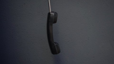 Payphone receiver swinging in space, unfinished phone call