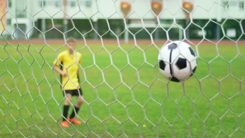 A young boy scores a goal during a penalty shoot out. Slow motion