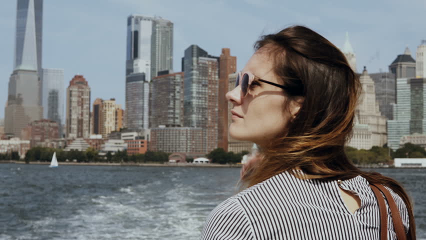 Young beautiful girl go for a boat through the East river in New York, America. Happy tourist on excursion in sunny day.