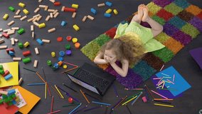 Cute curly girl using educational software on laptop, learning numbers at home