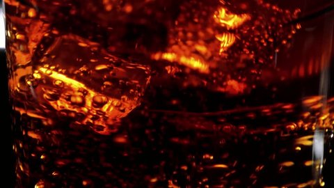 Floating ice cube in a glass of Cola - Soda drink in slow motion