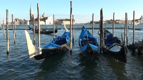 Three moored gondolas on the waves of the Venetian lagoon. Venice, Italy