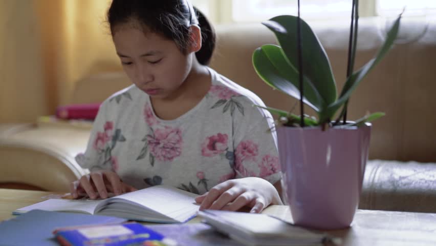 Young happy girl kid sitting and reading children book at table with plants. Turning book pages Royalty-Free Stock Footage #31406998