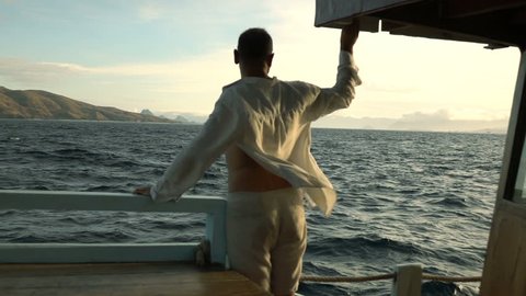 Man standing on the yacht and admires the view, slow motion shot at 240fps, steadycam shot
