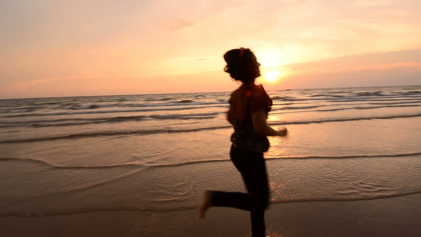 Silhouette Asian woman running on the beach at sunset