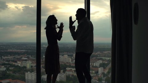 Silhouette of couple fighting, arguing by window at home, super slow motion 120fps
