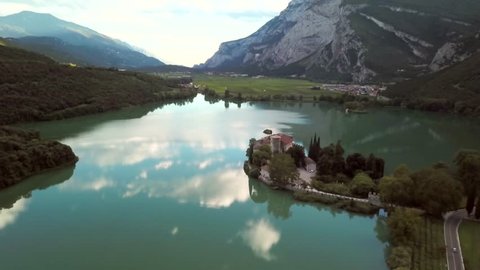 Castel Toblino Italy and lake aerial view. Flying above beautiful green lake towards Italian alps. 4k drone footage of majestic lake and forest in summer.