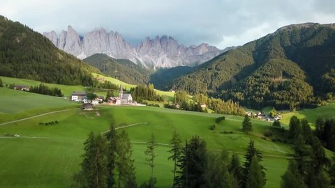 St. Magdalena Italy aerial view. Flying over small village of S. Maddalena with Swiss alps in background. 4k drone footage of picturesque mountain town with church in Italian alps in summer.