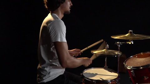 Turn the camera around the drums on which plays man drummer