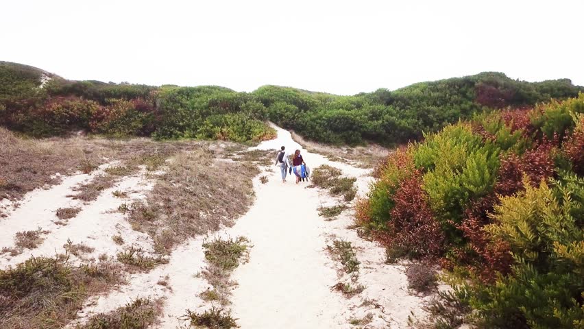 Young couple of friendly surfers walking to the beach for a morning surfing session.