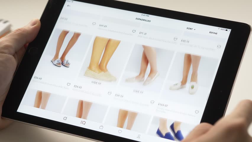 Shopping online on a tablet device looking to buy some woman's footwear. Browsing different choices.