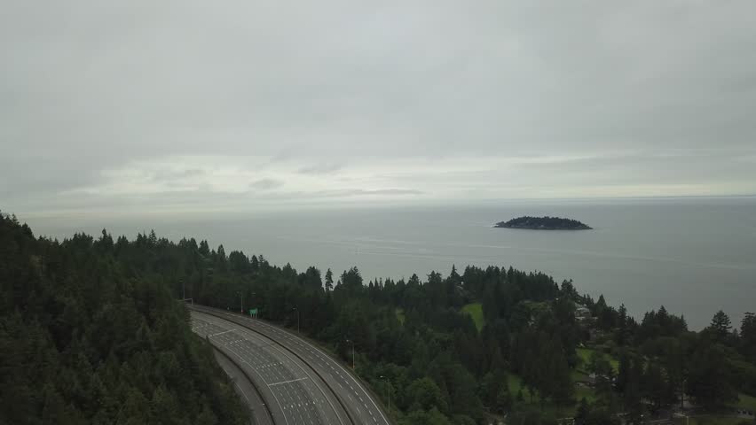 Aerial view of Horseshoe Bay and Sea to Sky Highway in West Vancouver, British Columbia, Canada. Taken during a wet and rainy summer day with an overcast sky covered in low clouds.