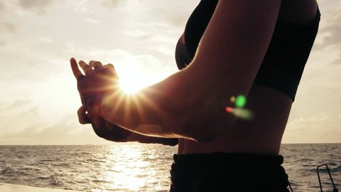 Closeup view of woman getting her fists ready for the boxing gloves by wrapping bandage around them standing against the sun. Female boxer wrapping hands with boxing wraps on the beach. Lens flare