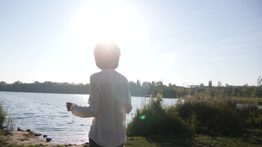 Happy relaxed girl in motorcycle helmet on the beach of the pond of old village or town.