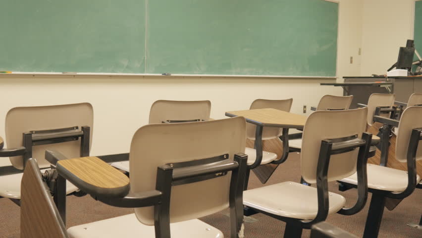 Push in towards blank chalkboard over empty school desks. The elementary school classroom has been abandoned. The campus has been evicted due to bullying, budget cuts, and lowered attendance rates. Royalty-Free Stock Footage #31451758