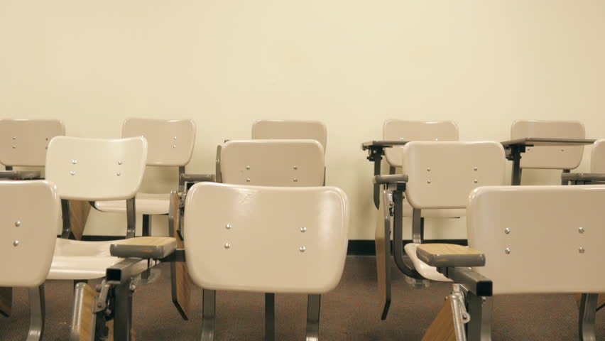 School's out for summer - or maybe fall break, winter vacation or spring break. The desks sit abandoned while students are out of school on hiatus. Handheld shot drifts over the empty desks. Royalty-Free Stock Footage #31451761