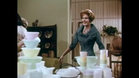 CIRCA 1958 - A hostess demonstrates Tupperware home products to guests at a party in a television commercial.
