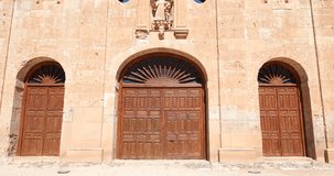 4k video. Tilt shot of landmark of facade, from door to sculpture of San Francisco de Asis in ancient convent, from thirteenth century, in old town of Ayllon village, in Segovia, Spain, Europe
