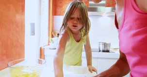 4k video. Four years old blonde child in the kitchen in teamwork with woman preparing onion raw to cook with potatoes
