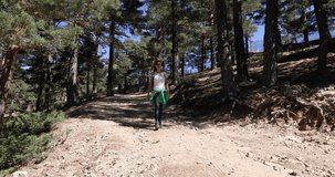 4k video. Pan shot, brunette sport woman with white shirt grey trousers walking or hiking or trekking on rural path in Navacerrada mountain, in Guadarrama Natural Park, Madrid, Spain 
