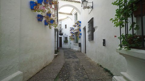 Smooth camera steady slide shot around old south Spain village narrow street, with white walls, beautiful facades with flowers, perfect for cinema digital composition or movie clips background