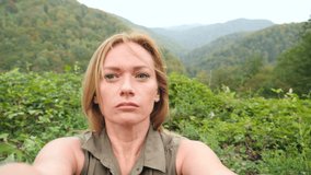 woman having video chat using smartphone outdoors on a background of mountains, sharing travel adventure friend's .Girl filming selfie video for social media. slow motion 4k
