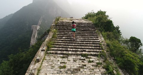 Aerial flying drone view of ultra marathon young fitness woman trail runner running on great wall