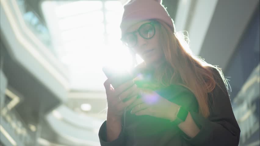 A young hipster female using app on the smartphone in the big mall Royalty-Free Stock Footage #31464625