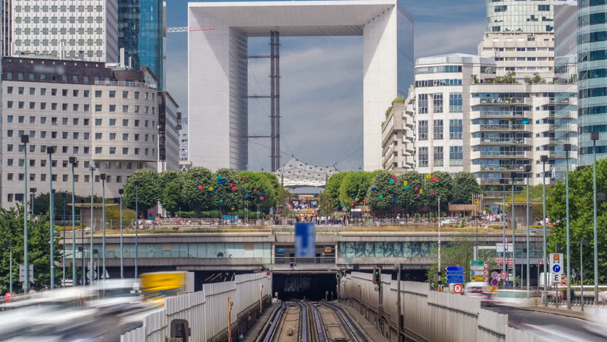 Office buildings in modern part of Paris - La Defense timelapse. Skyscrapers with rails of metro line and traffic on road. Paris, France