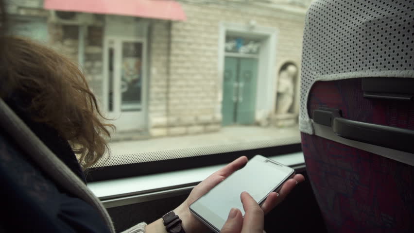 The girl uses the phone on the bus