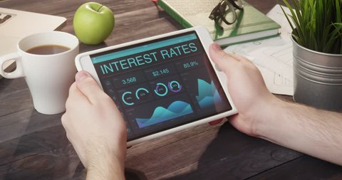 Checking interest rates data using tablet computer at desk