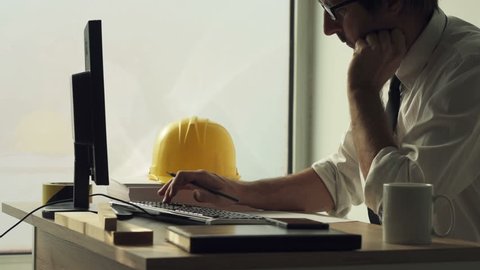 Construction engineer working on desktop computer using CAD software to sketch project in architecture studio office