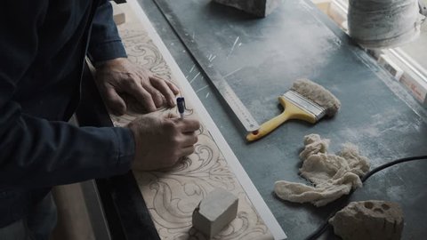 Worker traces lines with a stencil handle, the pattern is transferred to a marble slab using a carbon paper, a workplace, a sketch is drawn on lined paper