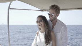 slow motion video happy smiling young rich couple in love driving together with catamaran yacht on sunny summer day out on mediterranean sea
