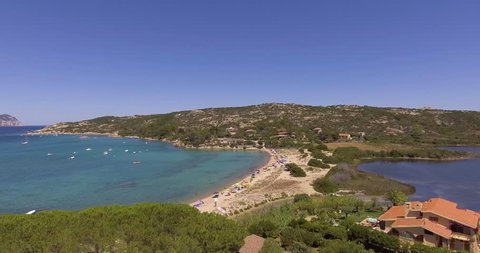 Aerial, beautiful bay in Sardinia with the beach with some beach umbrellas on it, 4K